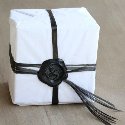 gift wrapped wedding ring box. The box is wrapped in tissue and carbon fibre with a black wax seal