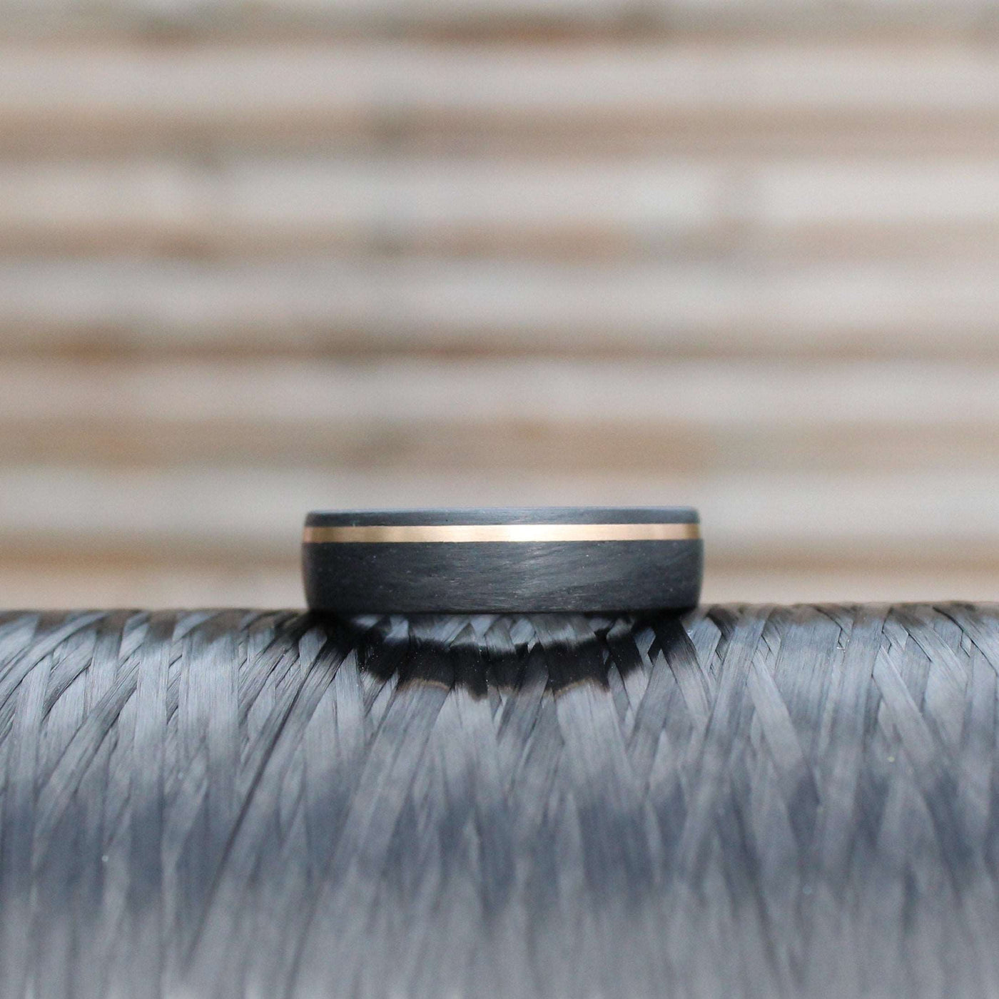 black carbon fibre wedding ring band. 6mm wide with a stripe of rose gold. black mans wedding ring uk