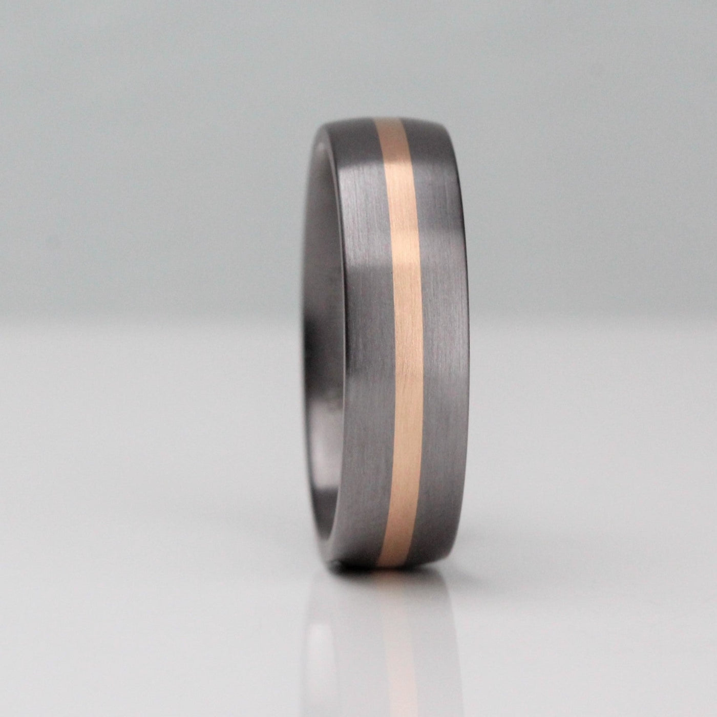 6mm wide tantalum wedding ring. With a 2mm cenrral stripe of rose gold. Tantalum has a gunmetal colour. court shape