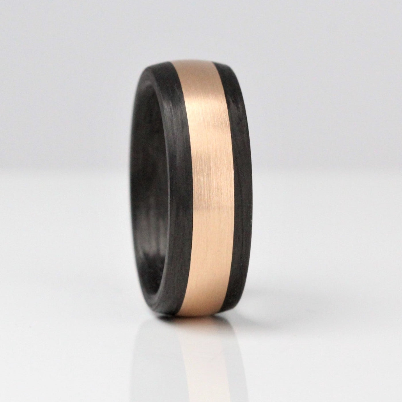 black carbon fibre wedding ring band. 8mm wide with a centre of rose gold. black mans wedding ring band uk