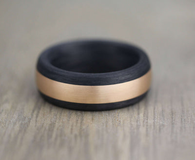 Black carbon fiber wedding band with a rose gold central inlay