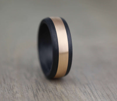 black wedding ring band made of carbon fibre with a wide rose gold inlay
