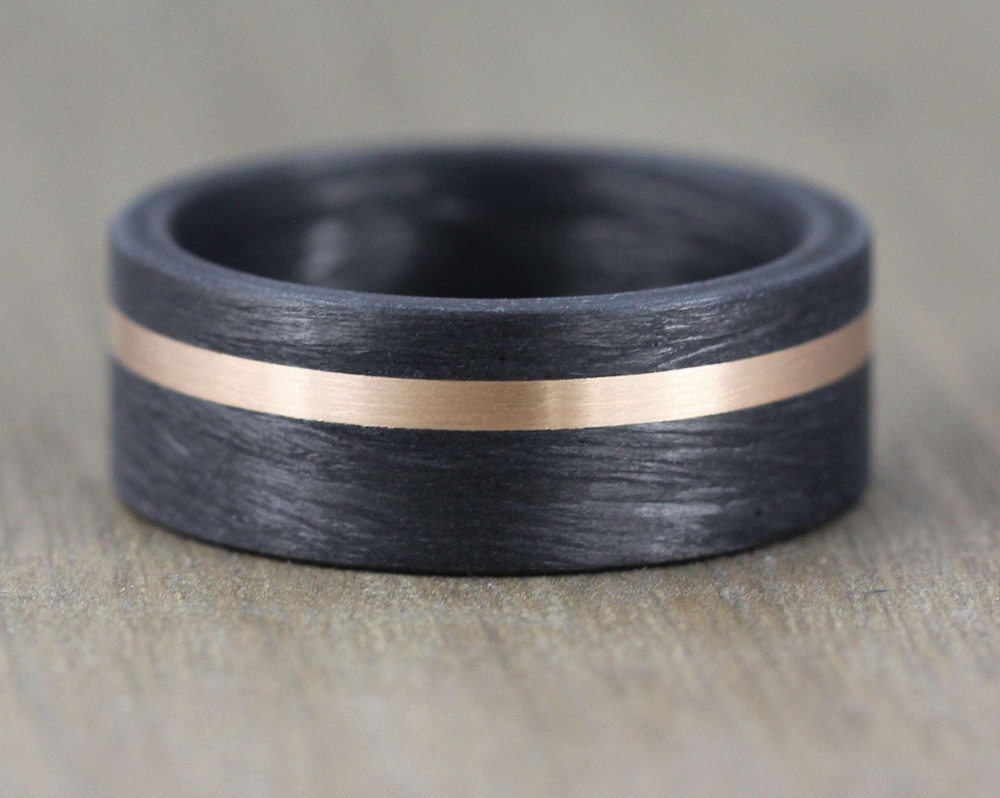 8mm Carbon Fibre wedding band with 2mm rose gold inlay. Comfort fit black carbon fibre wedding ring band. 8mm wide with a stripe of rose gold. black mans wedding ring uk