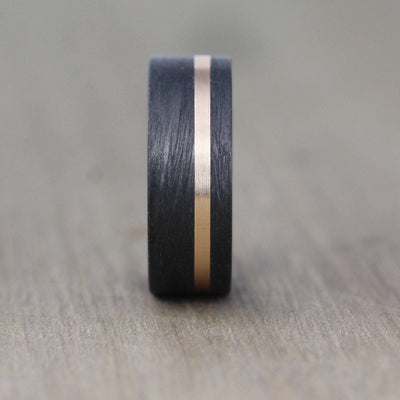 8mm wide black wedding ring with a 2mm rose gold inlay. black carbon fibre wedding ring band. 8mm wide with a stripe of rose gold. black mans wedding ring uk